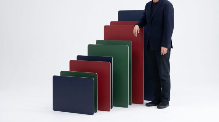 Advertiser standing beside a staircase of blank navy, red, and green cards, a vi Advertiser standing beside a staircase of blank navy, red, and green cards, a visual for stepped Meta ads scaling with no ad copy