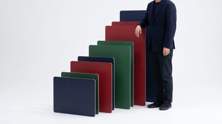 Advertiser standing beside a staircase of blank navy, red, and green cards, a visual for stepped Meta ads scaling with no ad copy